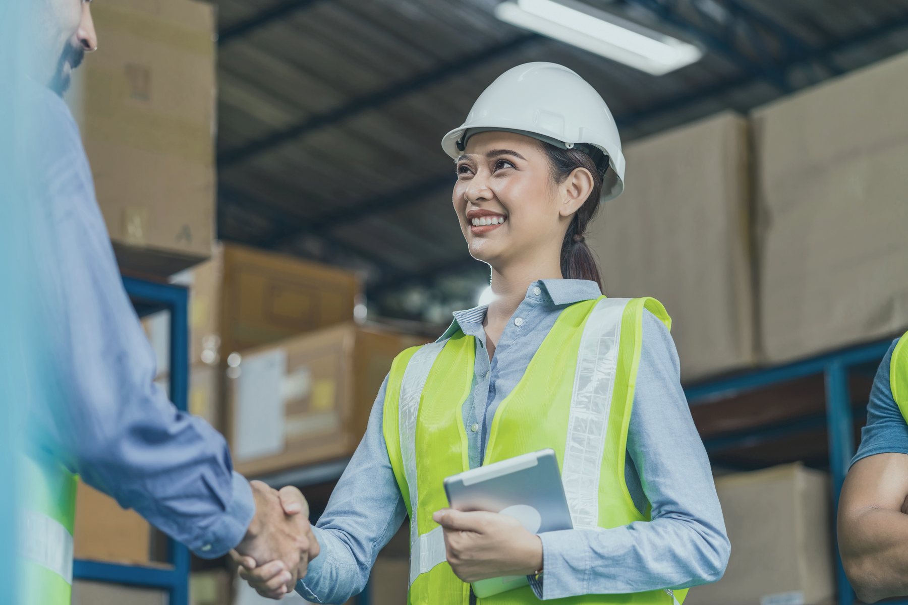 Operations manager in hi-vis and hard hat shaking hands on a warehouse floor