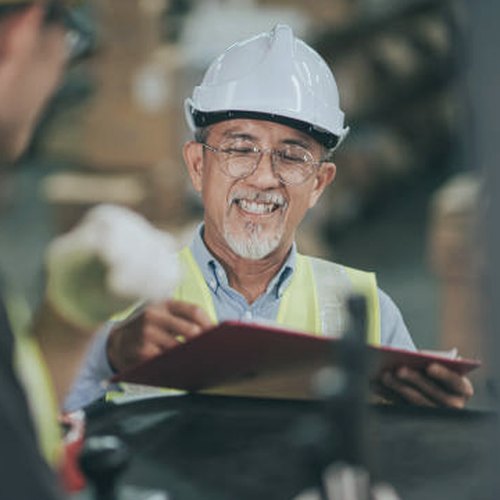 Site supervisor in hard hat reviewing a clipboard and smiling